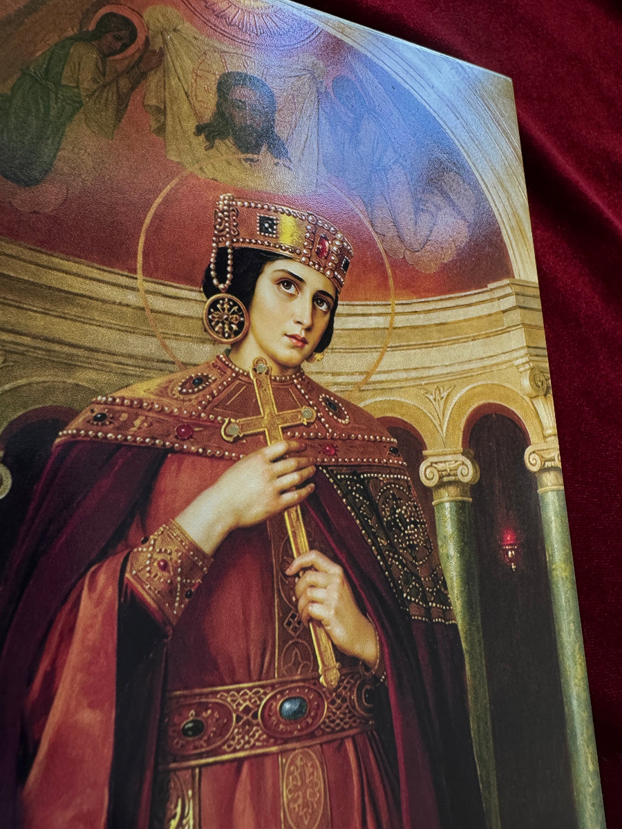A close-up of a religious art print or poster depicting a crowned saint Alexandra or king in ornate red and gold robes, holding a cross, with a halo and architectural background. The print is photographed against a dark red velvet-like fabric backdrop.