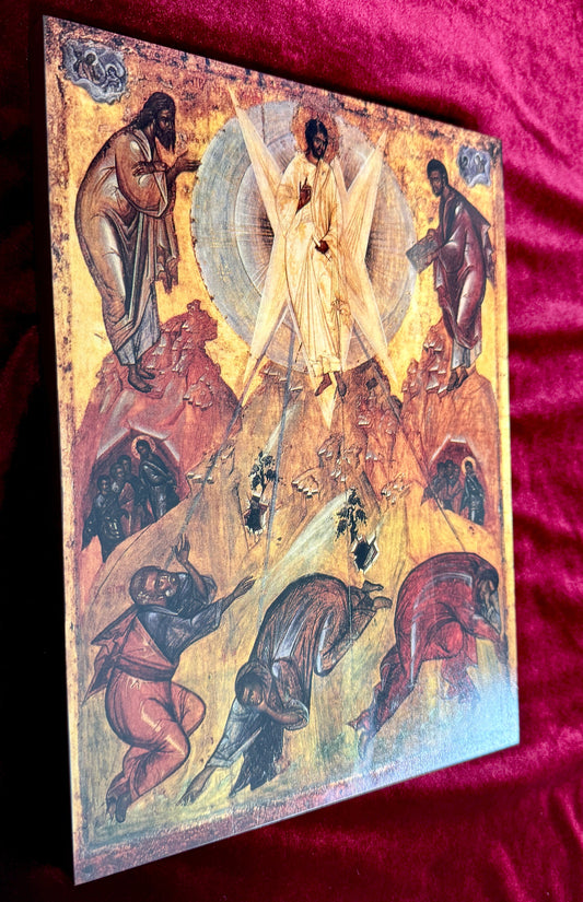 An Eastern Orthodox icon painting depicting the Transfiguration, mounted on a wooden panel and displayed on a red velvet fabric background.